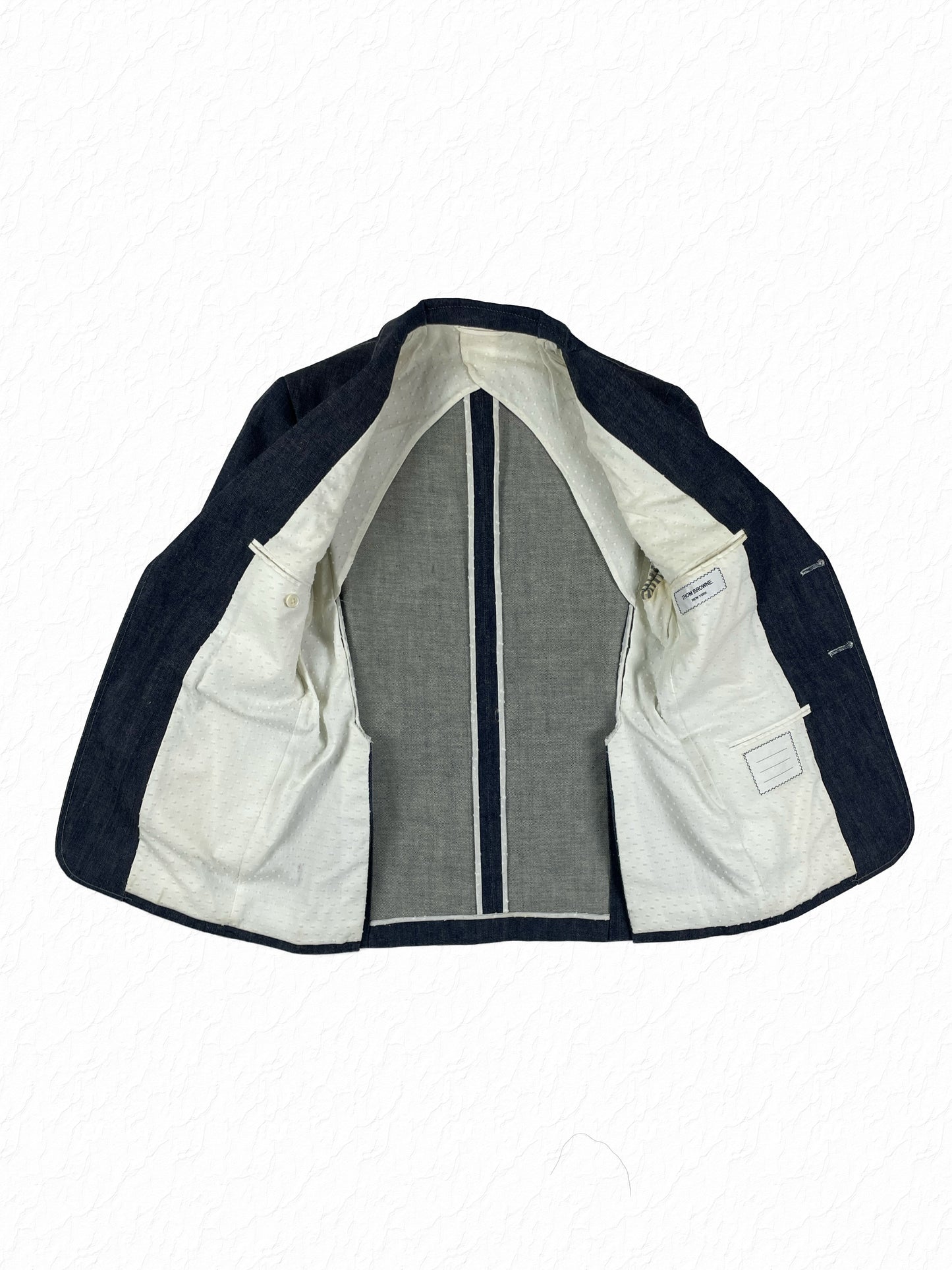 White dotted lining inside the Thom Browne indigo denim suit jacket