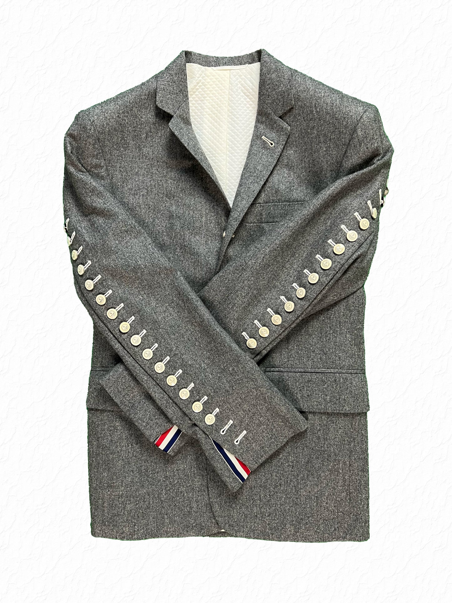 Functional arm fly buttons with RWB grosgrain tab on Thom Browne flannel jacket