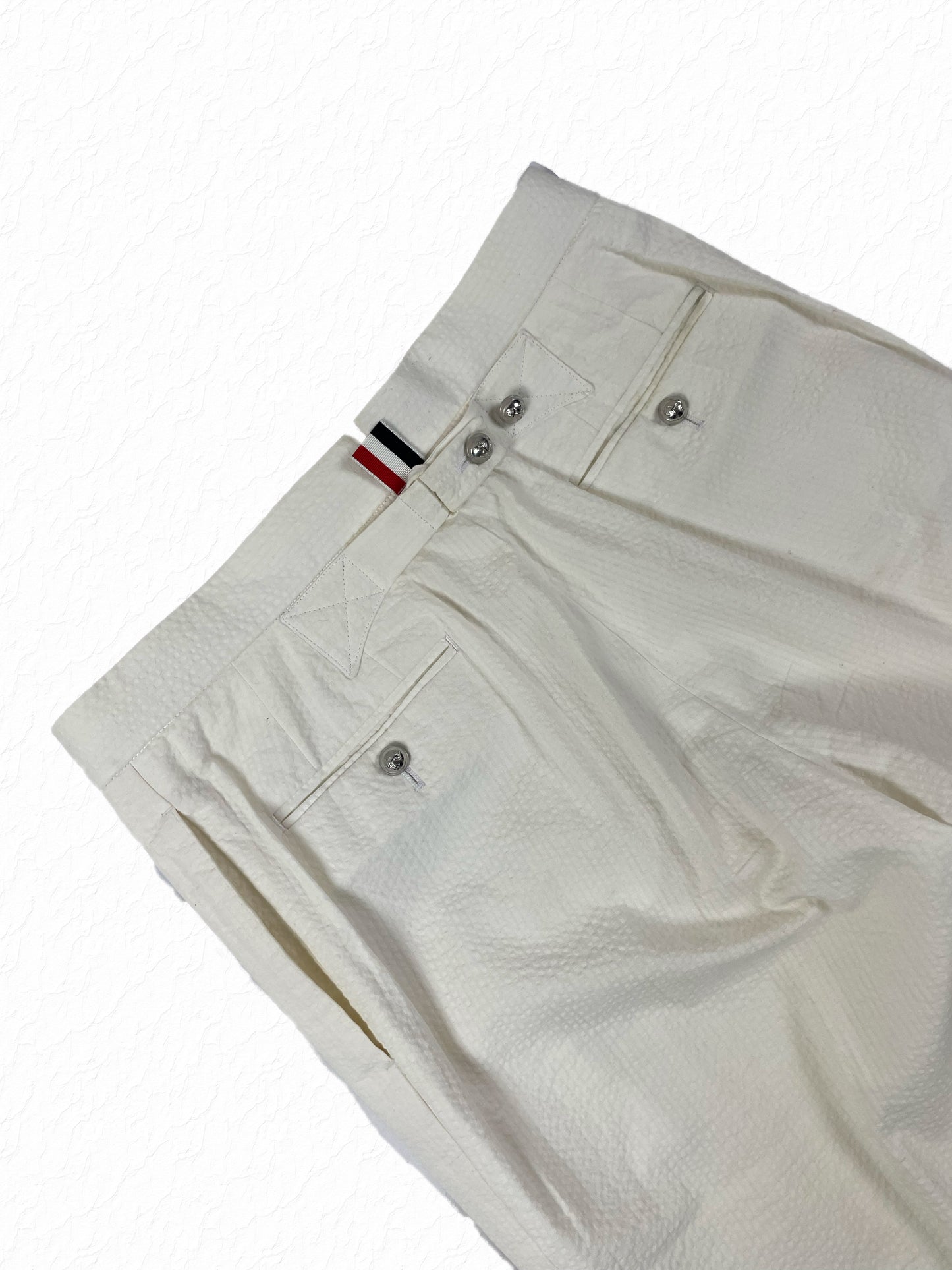 RWB grosgrain waist tab on Thom Browne white seersucker trousers