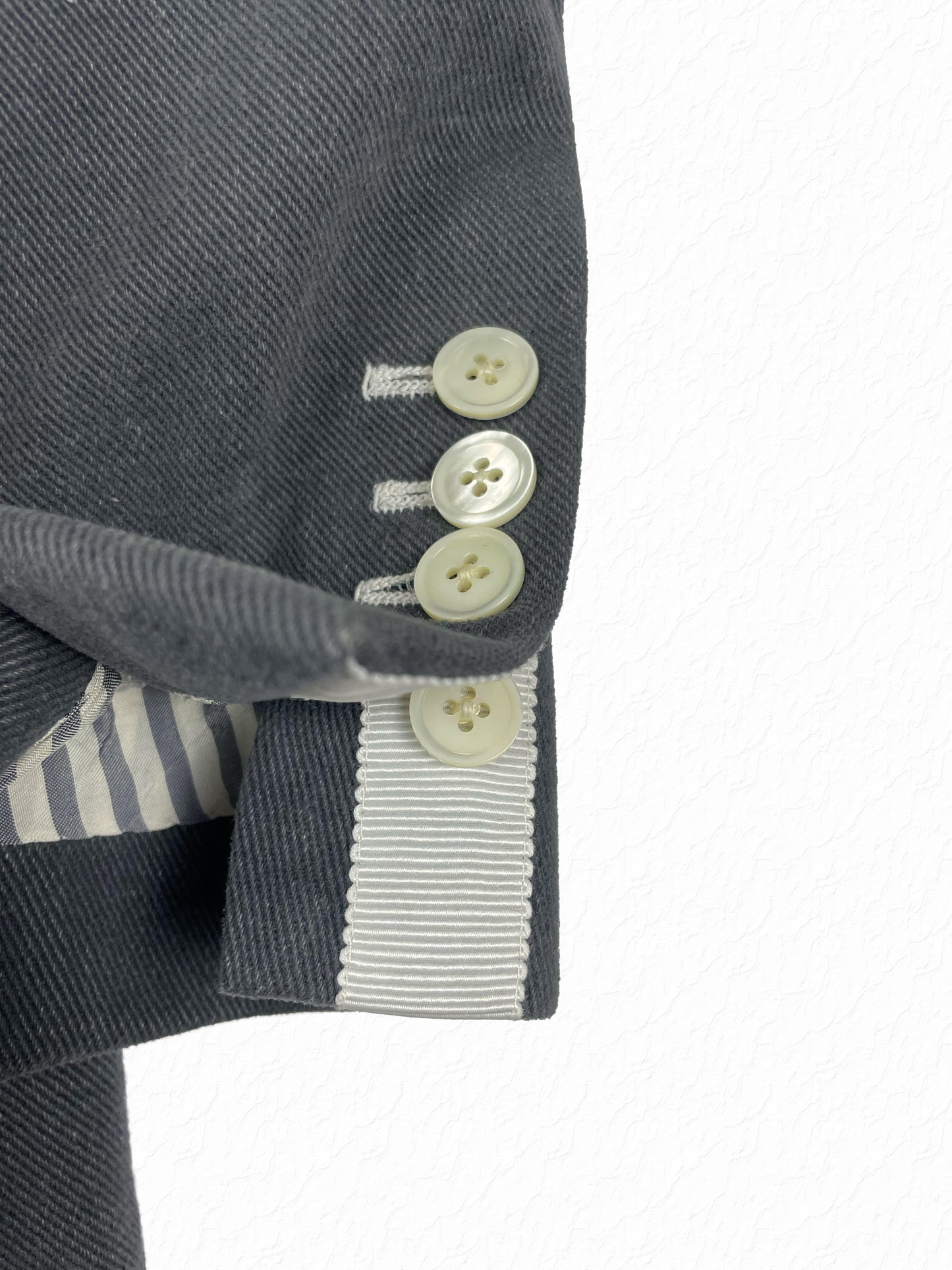 Mother of pearl four-button cuff with white grosgrain trim on Thom Browne overcoat