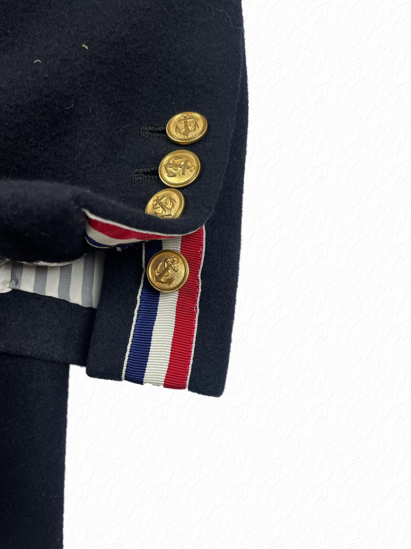 Gold anchor buttons and RWB grosgrain trim on Thom Browne wool overcoat