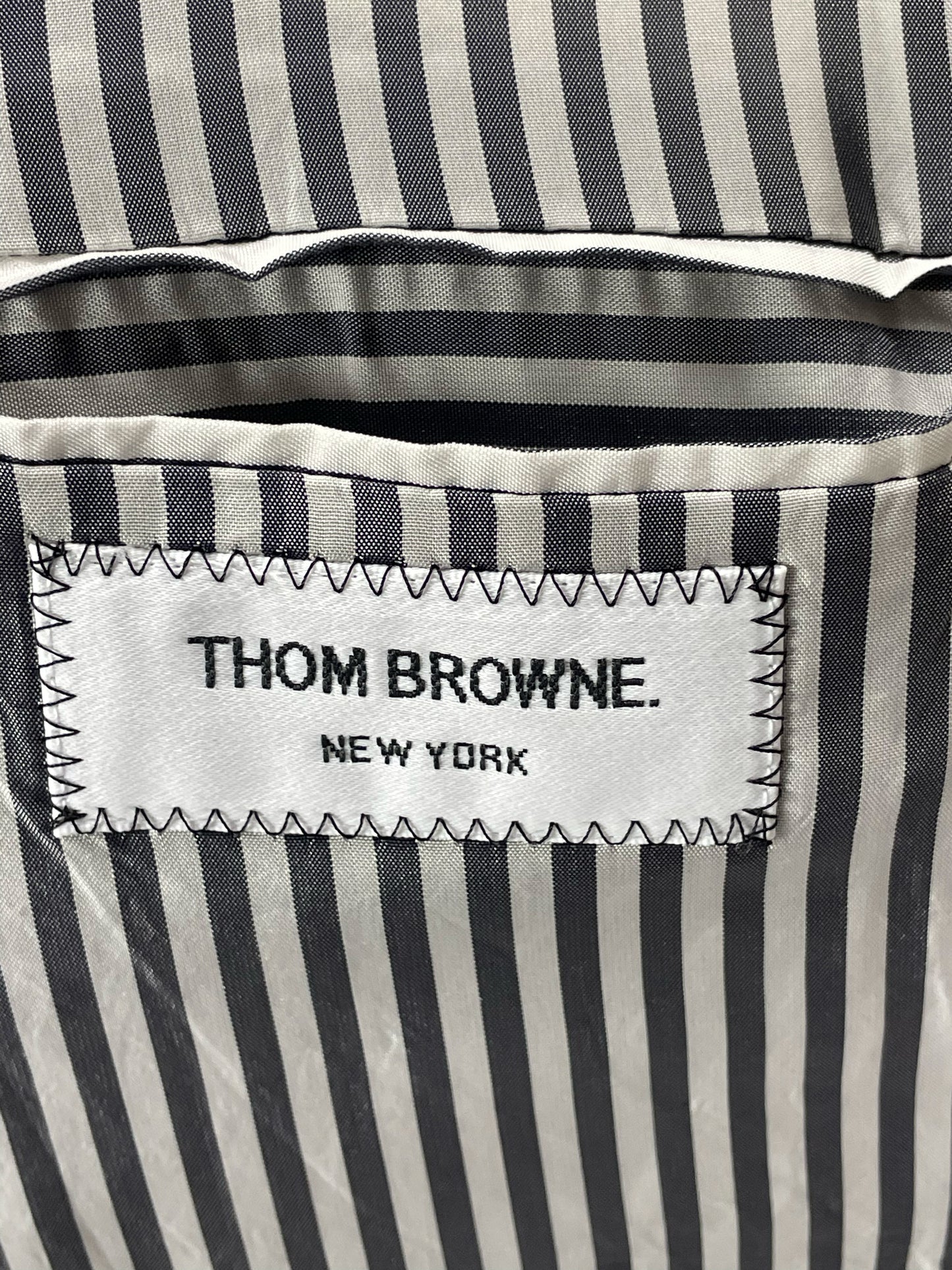 Thom Browne New York label on striped lining of grey blazer
