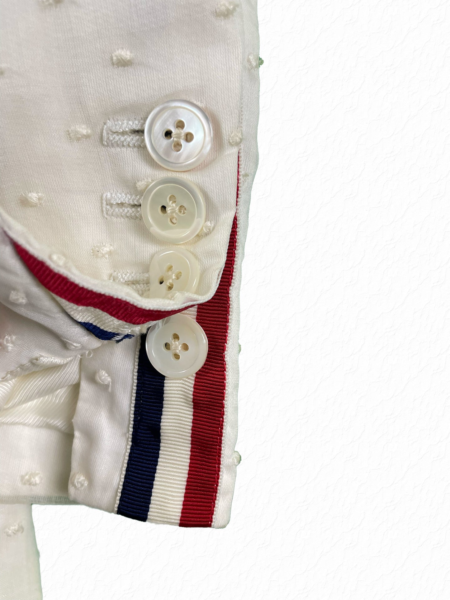 Mother of pearl buttons and RWB grosgrain tab on Thom Browne cotton sport coat sleeve