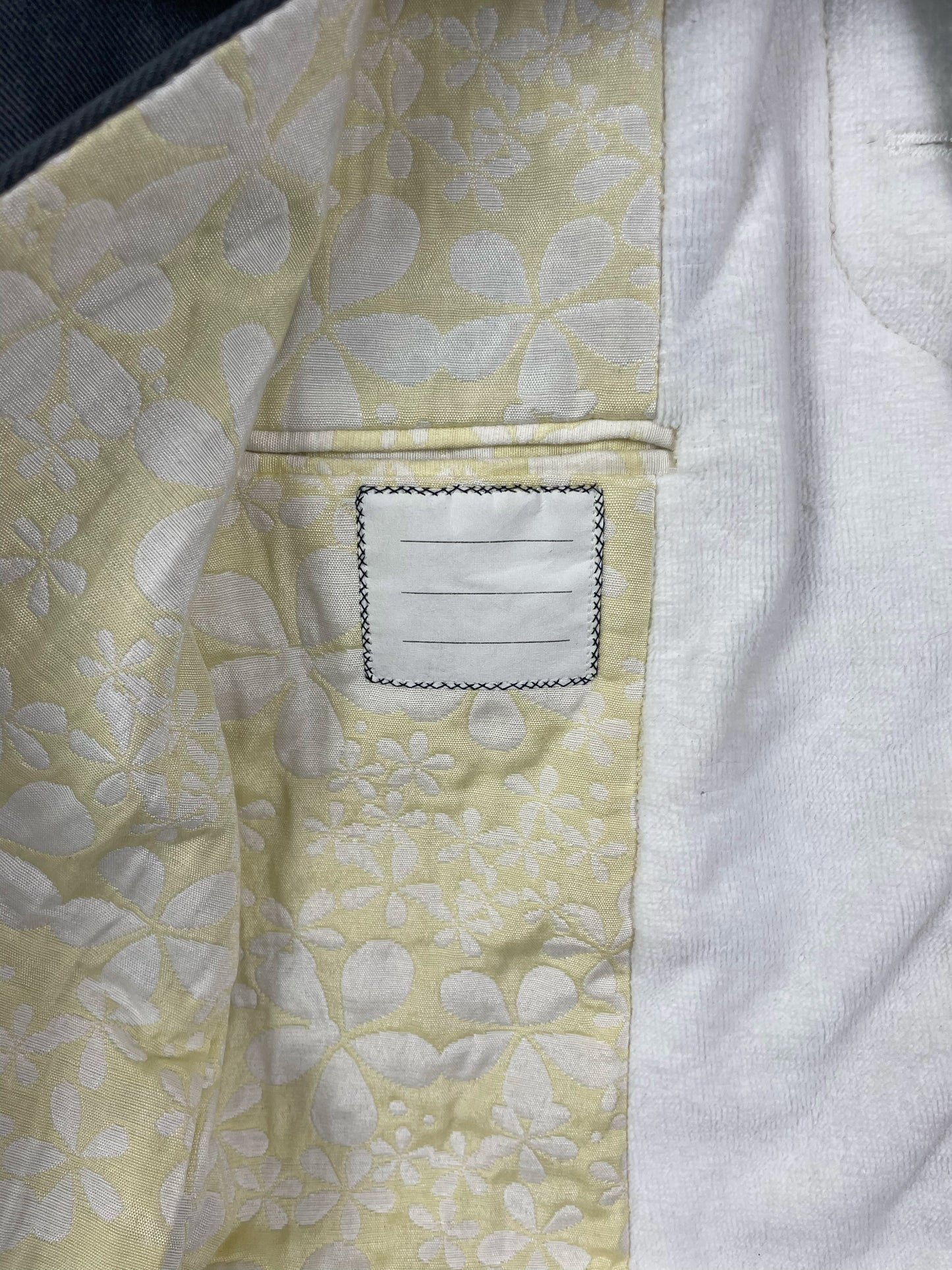 Pastel yellow floral stitched lining inside Thom Browne Chesterfield overcoat