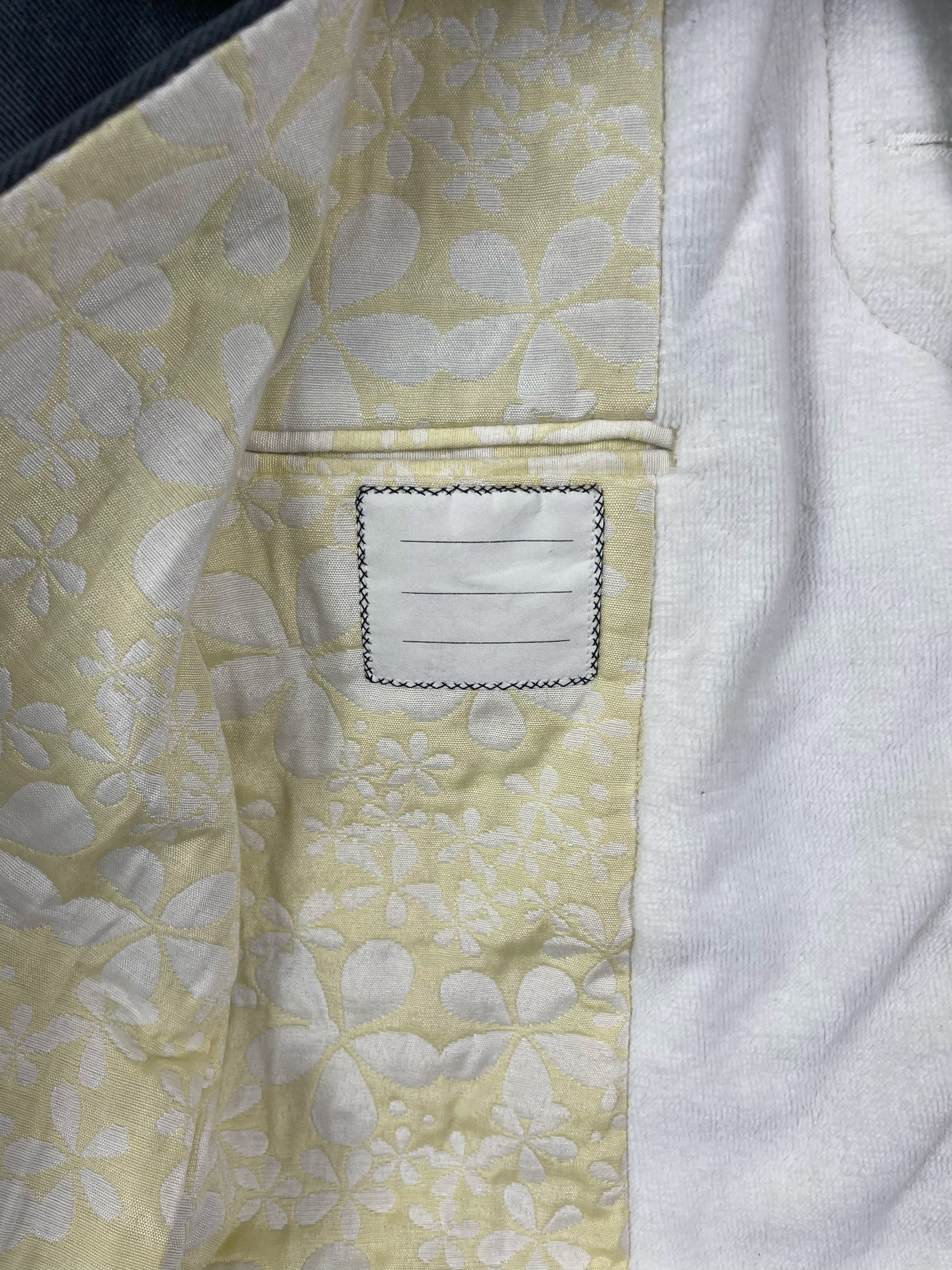 Pastel yellow floral stitched lining inside Thom Browne Chesterfield overcoat