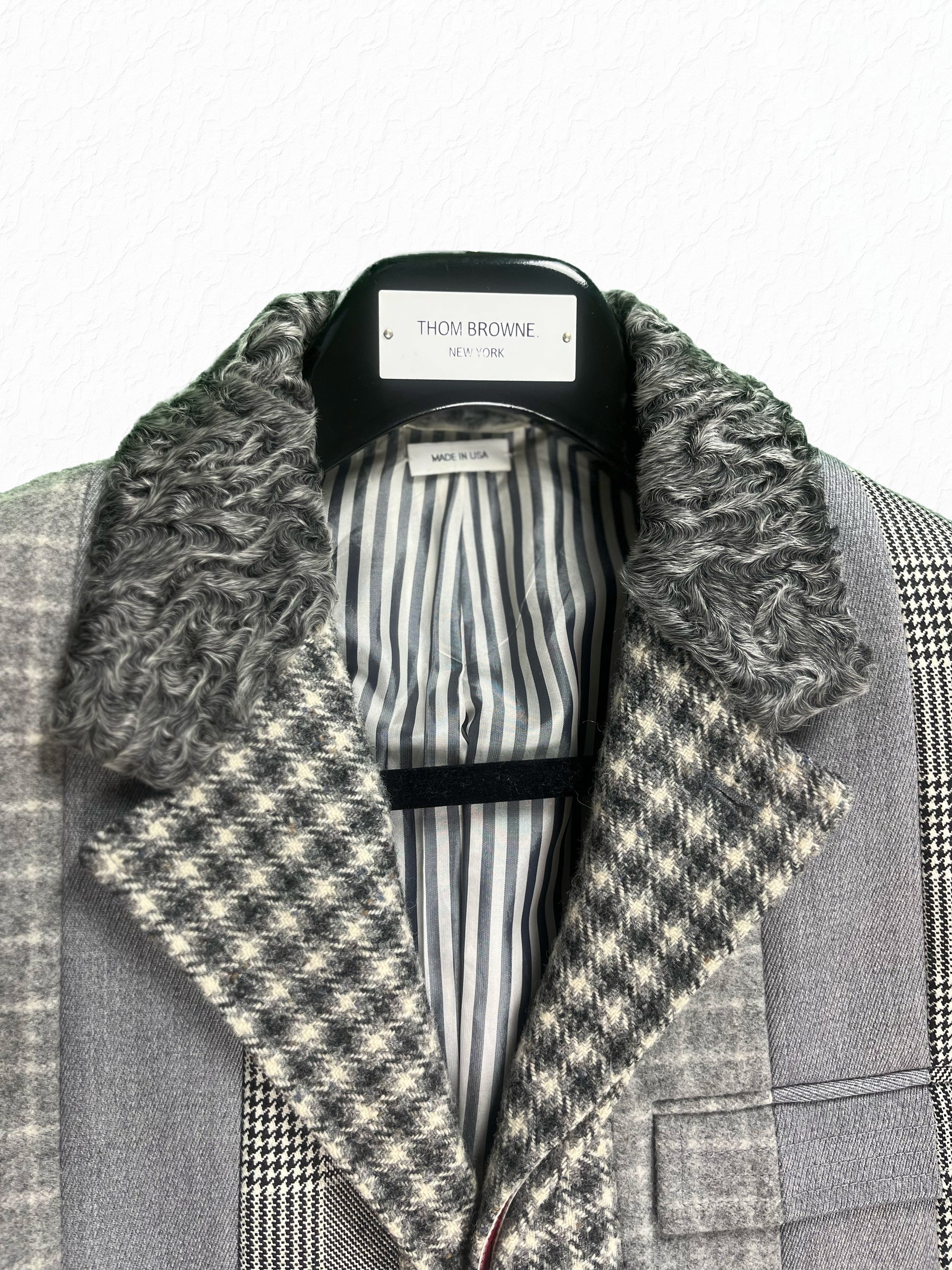 Grey striped lining and astrakhan collar on Thom Browne paneled overcoat